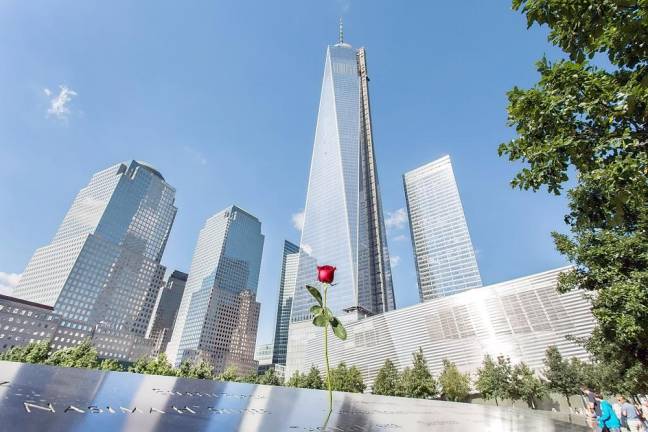 A red rose rises up from the 911 Memorial Wall of Names with the Freedom Tower in the background. Photo by Roger G. Breese.