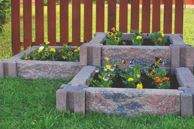 Courtesy of Infinity Lawn and Garden Incorporating raised flower beds using stone planters can beautify the landscape without taking a lot of time or effort.