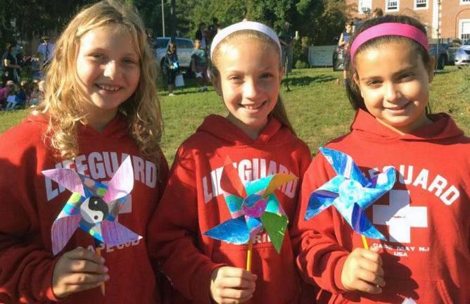 In matching, trendy Lifeguard hoodies with their peace pinwheels are Maya McColgan, left, Juliana Scanlon and Sophia Ruscillo.