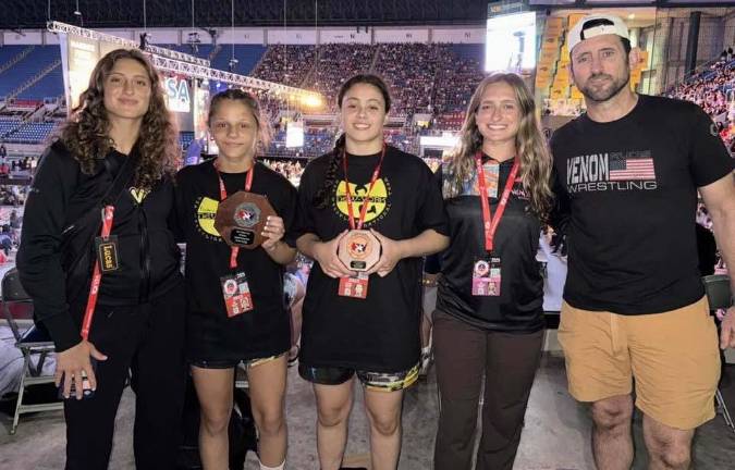 Warwick Valley High School's Victoria Alvarado, middle, and Monroe-Woodbury's Gail Sullivan are flanked by the Macalusos of Venom Girls Wrestling Club at last season's national championships in Fargo, N.D. (Photo provided)
