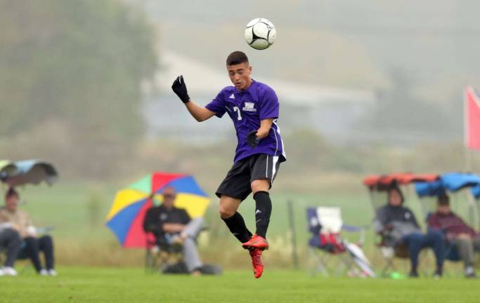 Photos by William Dimmit Connor Paik (#7) heads the ball in the mist.