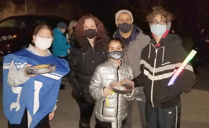 Dreidel Mascot Rivkah Burston delivers latkes, donuts and glow sticks to the Mosher family of Monroe at Chabad’s Hanukkah Drive-in Experience.