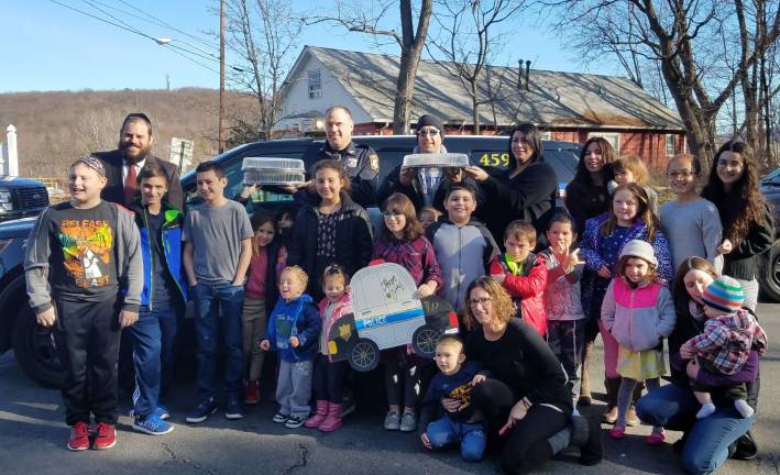 A group of Chabad Hebrew School students present Officer Joseph Ryle of the Monroe PD and Officer Loftus (Bronx PD) with cards and police-themed cookies. Officer Ryle gave students a full tour of the station as well as the opportunity to hear the sirens and explore his police car.