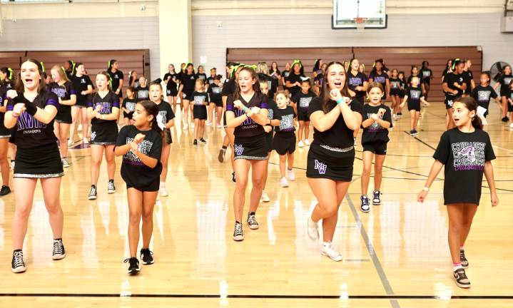 The young cheerleaders learn new cheers from the varsity team.