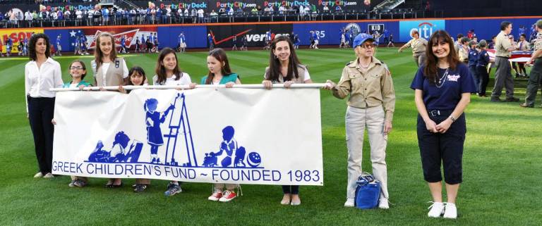 Tina Anastos, far right, of Monroe, coordinated the participation of local girl and boy scouts to be part of the opening flag ceremony at Citifield prior to last Saturday&iacute;s Mets games. Joining her with The Greek Children&iacute;s Fund banner are Woodbury Cadette Girl Scout Lisa Jacobsen and Monroe Cadette Girl Scout Heleena Anastos as well as other girl scouts from Port Jefferson and New Rochelle.