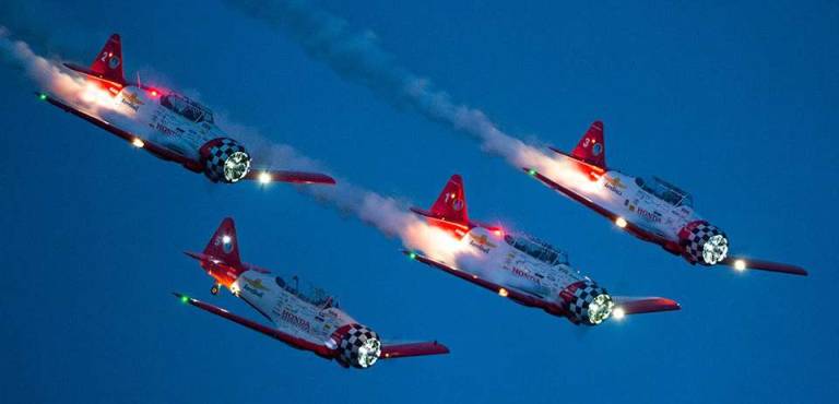 Airplanes perform during a nighttime show.