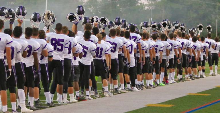 Photos by William Dimmit The Crusaders raise their helmets in salute during the National Anthem last Saturday night prior to their game against Kingston High School in Kingston.