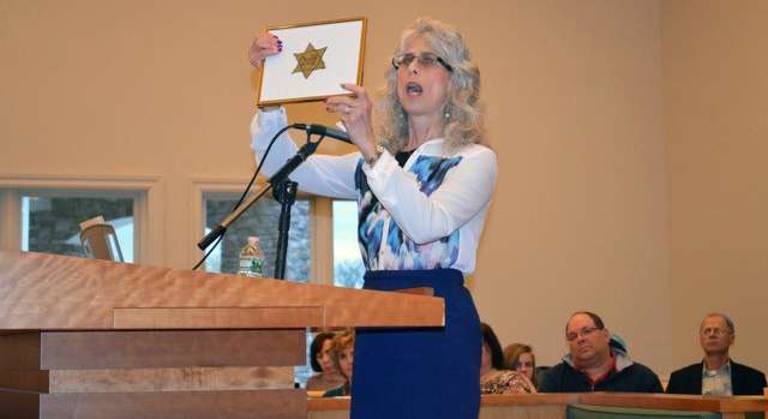 Lea Kaufer-Morganstein displays the Yellow Jewish Star that her mother, Cecile Kaufer, was forced to wear in France during World War II, at the Joint Yom HaShoah Commemoration at Eitz Chaim.
