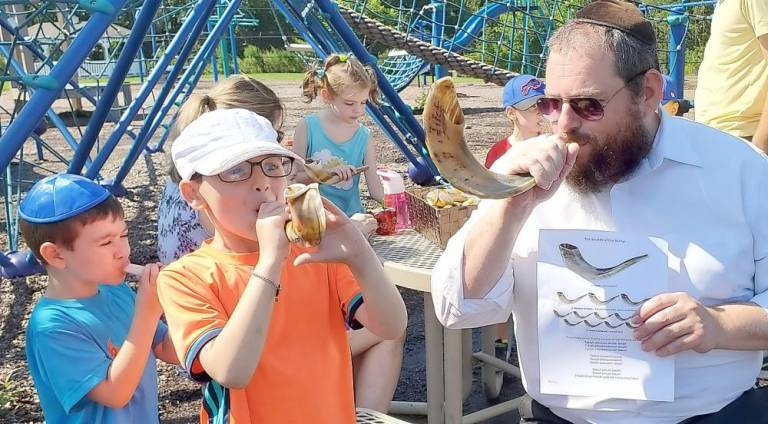 Rabbi Pesach Burston and Hudson and Ethan Mendelovitz of Central Valley sound the Shofar during a “Pre-High Holiday in the Park” event.