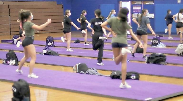 The cheer leaders practice their dance routine while maintaining their distance.