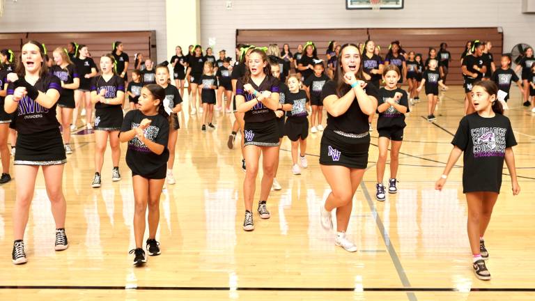 The young cheerleaders learn new cheers from the varsity team.