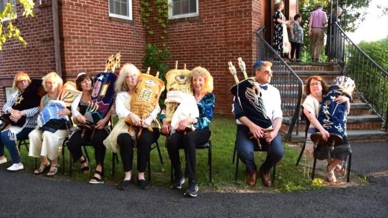 Congregants sit with the Torahs from Monroe Temple Beth-El, waiting to bring them inside the Temple Beth Shalom building.